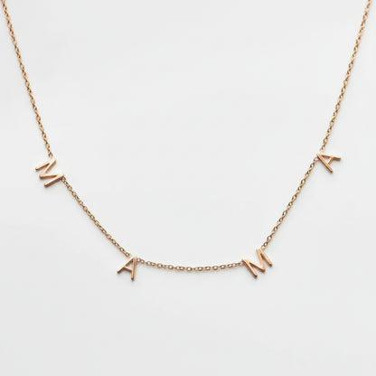 A delicate gold chain necklace featuring three small letter charms spelling 'MAMA' in gold, displayed against a clean white background.